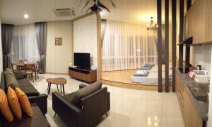 a living room with a couch and chairs and a bedroom at The Octagon Ipoh in Ipoh
