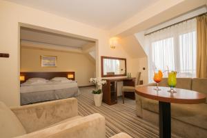 ヤロスワビエツにあるKról Plaza Spa & Wellnessのベッド、ソファ、テーブルが備わるホテルルームです。