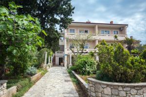 a house with a stone path in front of it at Apartmani Violic in Punat