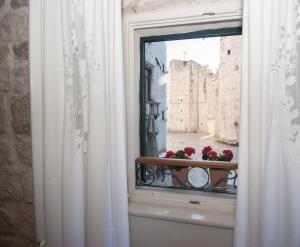 a window with red flowers on a balcony at Stone Pearl Heritage Premium Luxury Suite in Split