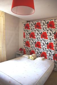 - une chambre avec un lit orné de fleurs rouges sur le mur dans l'établissement Gîte Meyer-Liss, à Ribeauvillé