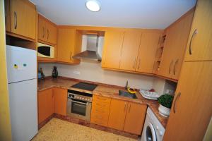 a kitchen with wooden cabinets and a white refrigerator at La Torre Orange Costa in Benicàssim