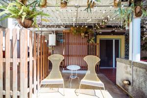 two chairs and a table in a room with plants at With Inn Hostel in Kaohsiung