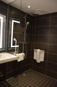 La salle de bains est pourvue d'une douche, d'un lavabo et d'un miroir. dans l'établissement Hôtel ORIGAMI, à Strasbourg