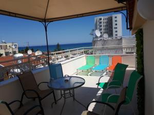 uma varanda com cadeiras e uma mesa no telhado em Panikos Beach Apartment I em Lárnaca