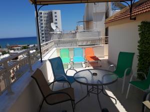 a balcony with a table and colorful chairs at Panikos Beach Apartment I in Larnaca