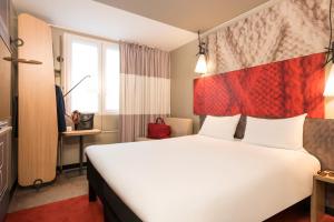 a hotel room with a large white bed and a window at ibis Bordeaux Centre - Gare Saint-Jean in Bordeaux