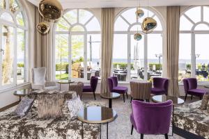 un vestíbulo con sillas y mesas de color púrpura y ventanas en SEETELHOTEL Strandhotel Atlantic en Bansin