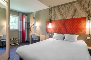a hotel room with a large bed and a desk at ibis Montauban in Montauban