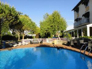 Logis Les Charmilles Chalon-sur-Saône Sud في Lux: مسبح كبير مع كراسي ومبنى