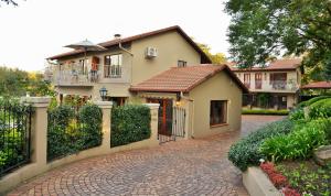a house with a gate and a brick driveway at Bellgrove Guest House Sandton in Johannesburg