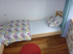 uma pequena cama num pequeno quarto com um lençol e almofadas em Gite Sent Martin em Roquefixade