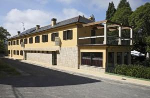 a large yellow building on the side of a street at Hotel O Casino da Rasa in Nogueira de Ramuin