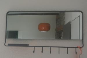 un espejo colgado en una pared con una luz roja en A Cà balade in Design, en Miglieglia
