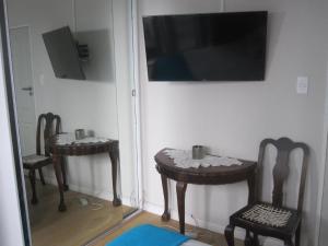 a room with two tables and two chairs and a television at 20 belladonna avenue Vredehoek Cape town in Vredehoek