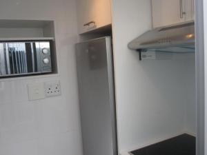 a small kitchen with a refrigerator and a microwave at 20 belladonna avenue Vredehoek Cape town in Vredehoek
