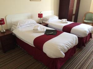 two beds in a hotel room with a laptop on them at New Birchfield Hotel in Weston-super-Mare