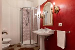 un bagno rosso con lavandino e doccia di Bellezza Suites a Cagliari