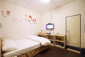 a bedroom with a bed and a desk with a television at Zhongshan Hostel in Fenqihu