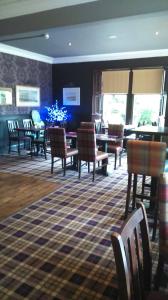 a living room with chairs and tables and a dining room at Burnett Arms in Inverurie