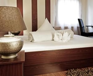 ein Bett mit weißer Bettwäsche und Kissen sowie einer Lampe in der Unterkunft Hotel Riviera in Ludwigsburg