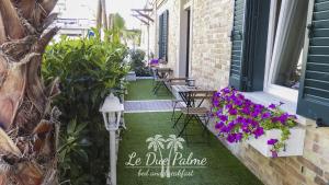 un patio con tavoli, sedie e fiori viola di Le Due Palme a Montesilvano