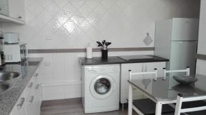a kitchen with a washing machine and a table at Alojamento S. Pedro in Peniche