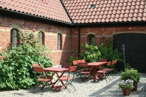 un patio con tavoli e sedie rossi di fronte a un edificio in mattoni di Blåsingsborgs Gårdshotell på Österlen a Kivik