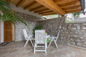 a patio with two white chairs and a table at Giardino dei Limoni in Toscolano Maderno