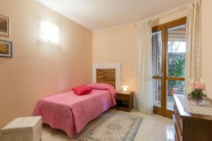 a bedroom with a bed with a pink blanket and a window at Giardino dei Limoni in Toscolano Maderno