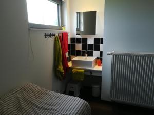 a small bathroom with a sink and a bed at Vakantiewoning Klavertje Lier in Lier