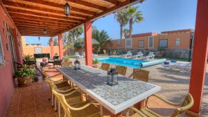 a patio with a table and chairs and a pool at Villa Romana in Caleta De Fuste