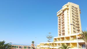 a tall white building with palm trees in front of it at Torres del Sol Playa de Las Vistas FREE WIFI in Playa de las Americas
