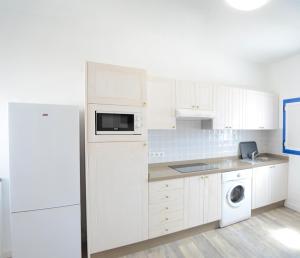 a white kitchen with a refrigerator and a microwave at Apartamentos El Marinero - Salado in Caleta de Sebo