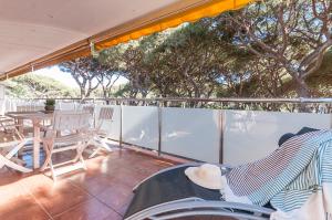 balcón con mesa, sillas y árboles en Lets Holidays Castelldefels Diagonal Orient, en Castelldefels