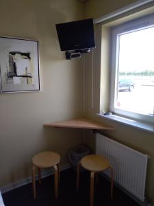 a desk and two stools in a room with a window at Motel Lyren in Padborg