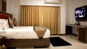 ein Schlafzimmer mit einem Bett und einem Fernseher darin in der Unterkunft GK PALACE Pure VEG Hotel in Jorhat + 66 Fotos