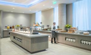 a woman standing in front of a buffet line with food at Maldron Hotel Belfast City in Belfast