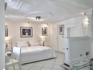 a white bedroom with a bed and a tv at Kramwinkelsuite Regensburg in Regensburg