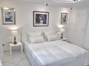 a white bedroom with a white bed and two lamps at Kramwinkelsuite Regensburg in Regensburg