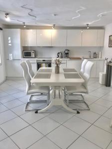 eine Küche mit einem weißen Tisch und weißen Stühlen in der Unterkunft Kramwinkelsuite Regensburg in Regensburg