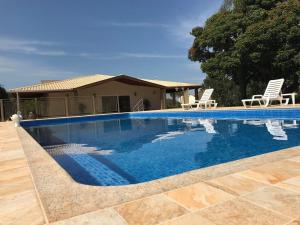 una piscina con sillas y una casa en Hotel Kaeru, en Avaré