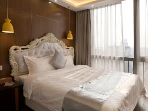 a bedroom with a white bed with a large window at Boman Holiday Apartment Bei Jing lu Jie Deng Du Hui Branch in Guangzhou