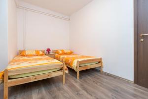 two twin beds in a room with wooden floors at Apartman Alberti in Labin