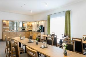 a restaurant with wooden tables and chairs and a kitchen at Hotel Kern garni in Walddorf