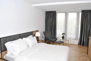 a bedroom with a large white bed and a chair at Prime Hotel in Tirana