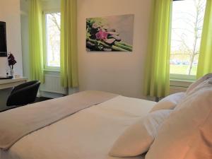 a bedroom with a white bed with green curtains at Hotel & Restaurant Schützen in Rastatt