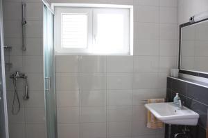 ein Badezimmer mit Dusche und Waschbecken und einem Fenster in der Unterkunft Apartment Pinta in Pag