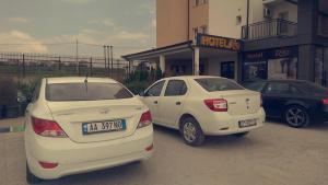 zwei weiße Autos, die vor einem Gebäude geparkt sind in der Unterkunft Hotel Rio in Pristina