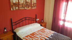 ベナルマデナにあるApartamento Corbousierの赤い壁とカーテンが備わるベッドルームのベッド1台